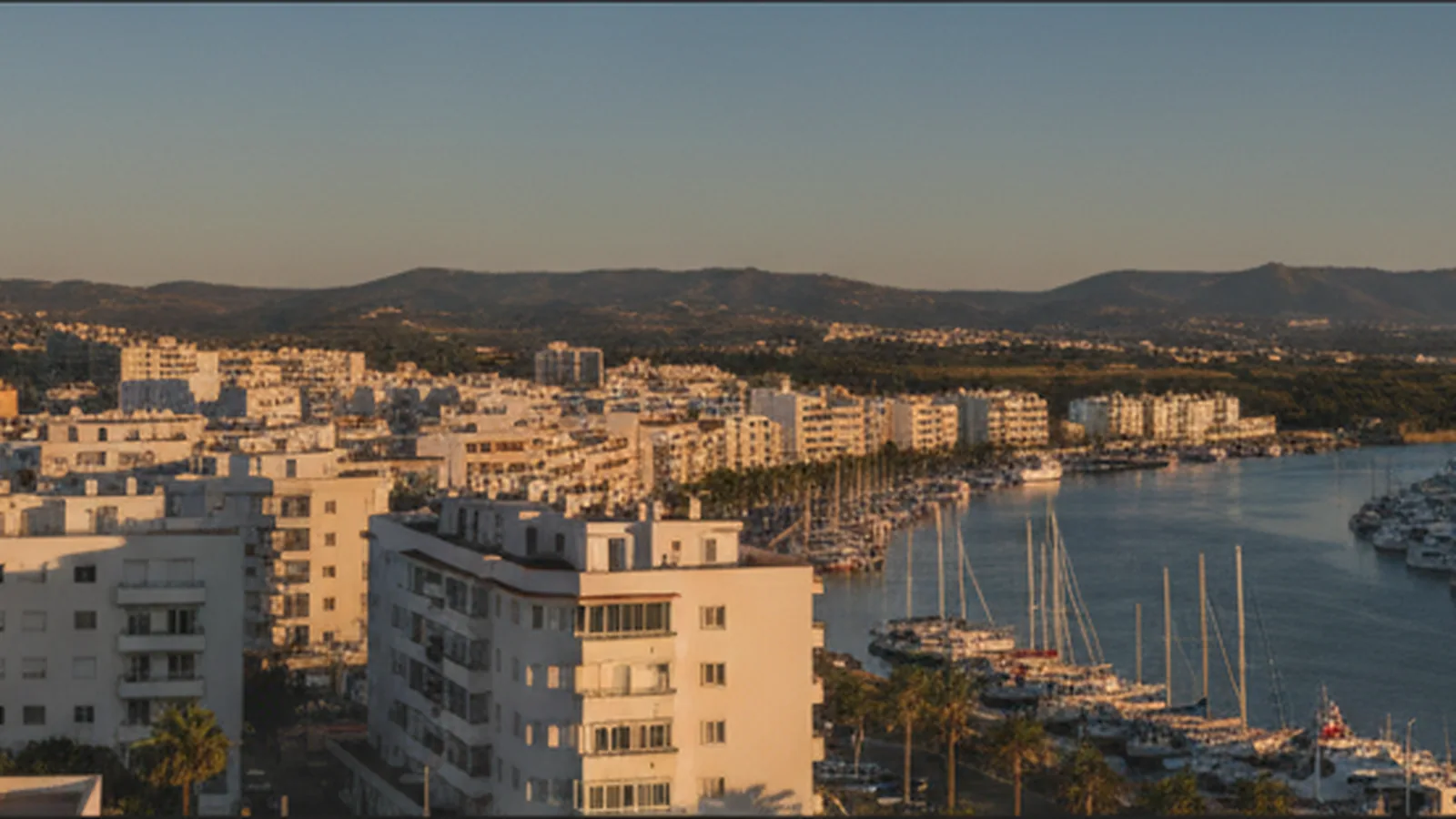 Vista de Portimão ao fim da tarde, com edifícios de habitação junto ao estuário